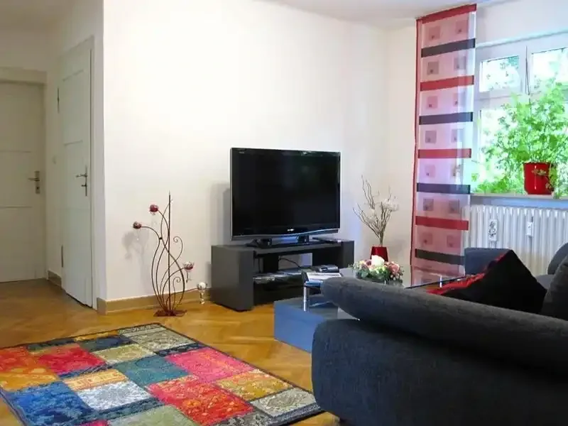 wohndiele mit cbequemer couch einem teppich und tv flachbildschirm sowie einer grossen zimmerpflanze